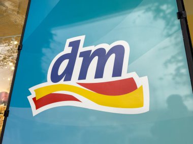 Villach, Avusturya - 23 Ekim 2025: Dm logosu, marka kimliğini vurgulayan ve müşteri ilgisini çeken parlak bir vitrin levhasında yer almaktadır.