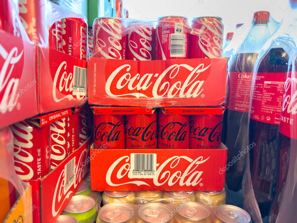 Villach, Austria - October 23, 2025: Stacked Coca-Cola cans in a colorful display, featuring different flavors and packaging in a retail setting