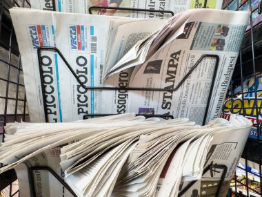 Tarvisio, İtalya - 17 Ekim 2025: Canlı bir gazete bayiinde çeşitli manşetler ve makaleler içeren bir tel askıda çeşitli gazeteler düzenlendi