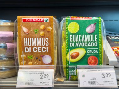 Tarvisio, İtalya - 17 Ekim 2025: Humus di Ceci ve Guacamole di Avokado süpermarket raflarında taze malzemeler ve canlı renklerin altını çizerek cazip bir şekilde paketlenmişlerdir.