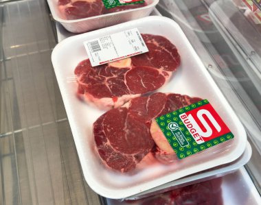 Tarvisio, İtalya - 17 Ekim 2025: Taze biftekler plastik tepsilerde fiyat etiketleri ile güzelce düzenlenir, bakkal ortamında kaliteli etin altını çizilir