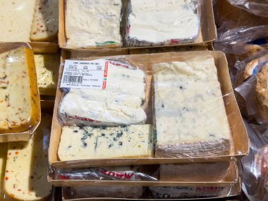 Tarvisio, İtalya - 17 Ekim 2025: Açık ambalajlı çeşitli peynirler, kremsi dokularını ve çekici renklerini vurgulamak üzere bir bakkalda düzenli olarak düzenlenir