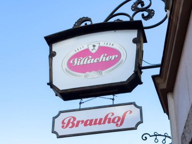 Villach, Avusturya - 29 Ekim 2025: Illacher Brauhof tabelası belirgin bir şekilde mavi gökyüzüne karşı sergileniyor, klasik tasarımı ve hoş karşılama ortamını vurguluyor