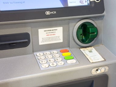 Villach, Avusturya - 29 Ekim 2025: ATM makinesi güncel kentsel bir ortamda uygun bankacılık hizmetleri sunan tuş takımı ve kart yuvası sergiliyor