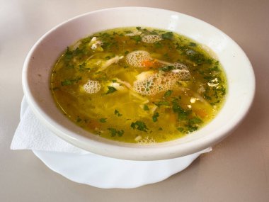 Sebzeli tavuk çorbası. Masada beyaz seramik kâse var..