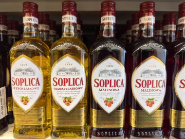 Klagenfurt, Avusturya - 29 Ekim 2025: Orzech Laskowy ve Malinowa aromalı Soplica votka şişeleri, perakende rafında güzelce düzenlenmiştir