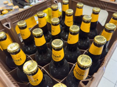 Klagenfurt, Avusturya - 29 Ekim 2025: Rozel bira şişeleri bir sandıkta organize edilir, parlak sarı başlıklar ve koyu camlar pazarlama için idealdir