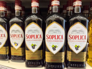 Klagenfurt, Avusturya - 29 Ekim 2025: Soplica kuşüzümü likörü şişeleri bir mağaza rafında düzgünce düzenlenmiş, çekici tasarımlarını ve markalarını ön plana çıkarıyor