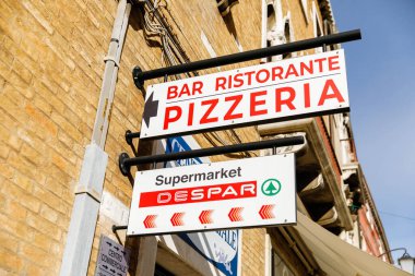 Murano, İtalya - 21 Kasım 2024: Murano, İtalya 'da pizzacı tabelası, taşralı tuğla bir duvarda koyu kırmızı harflerle gösteriliyor ve konuklar yerel lezzet ve atmosferi deneyimlemeye davet ediliyor.