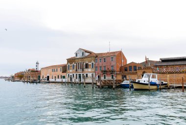 Murano, İtalya - 21 Kasım 2024: Renkli binalar Murano adasının rıhtımında, geleneksel mimariyi yansıtıyor ve huzurlu bir ortam sunuyor