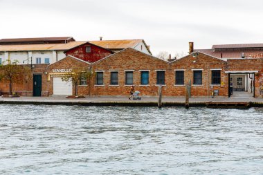 Murano, İtalya - 21 Kasım 2024: Tarihi tuğla binalar ve sakin suların yer aldığı, Venedik cazibesi ve kültürünün vücut bulduğu Murano Adası manzarası