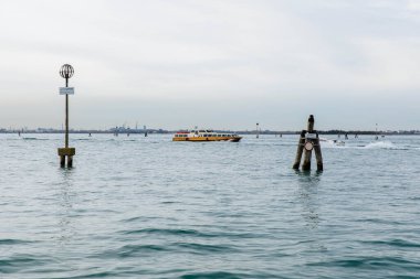 Murano, İtalya - 21 Kasım 2024: Murano Adası 'nın sakin sularında yüzen su taksisi, navigasyon işaretleri ve barışçıl bir atmosferle çevrili