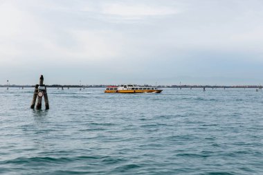 Murano, İtalya - 21 Kasım 2024: Murano Adası yakınlarındaki sakin sularda süzülen su taksisi Venedik manzarasının barışçıl atmosferini vurguluyor