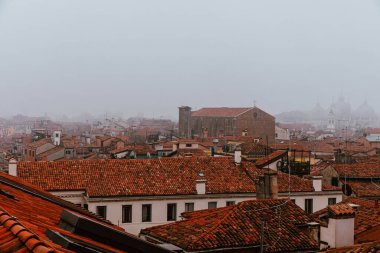 Venedik, İtalya - 20 Kasım 2024: Venedik 'in terasotta fayanslarıyla kaplı, sisle kaplı çatıları, şehrin tarihsel cazibesini ve sakin atmosferini vurguluyor