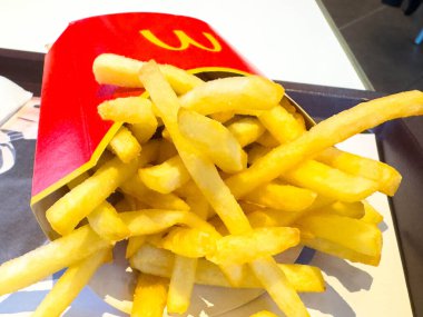 Villach, Avusturya - 10 Kasım 2025: McDonald 's kızartmaları çıtır çıtır dokularını ve fast food hayranları için lezzetli cazibelerini vurgulayan klasik kırmızı bir karton içinde yığılmıştır.