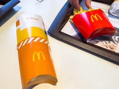 Villach, Avusturya - 10 Kasım 2025: McDonald 's yemeği tepside patates kızartması ve McWrap, renkli ambalaj ve davetkar yemek deneyimi