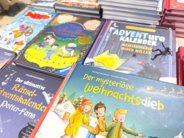 Villach, Avusturya - 10 Kasım 2025: Bir masada sergilenen macera temalı çocuk kitaplarının canlı çeşitliliği, genç hayal gücü için mükemmel