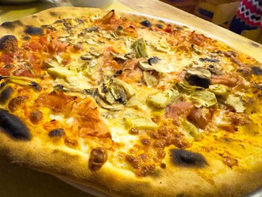 Lezzetli İtalyan pizzası, jambon, mantar ve ahşap masa üzerinde enginar..