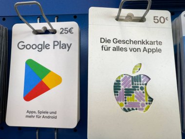Villach, Avusturya - 12 Kasım 2025: Google Play ve Apple hediye kartları, mobil kullanıcılar için dijital hizmetleri ön plana çıkaran bir rafta sergilenmektedir