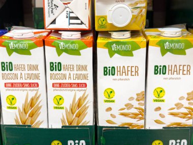 Villach, Avusturya - 12 Kasım 2025: Vemondo yulaf içeceği kutuları bir rafa dizilir, organik ve vejetaryen özellikleri çekici ambalaj tasarımı ile vurgulanır