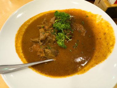 Taze otlarla süslenmiş bir kase lezzetli köri, zengin lezzetler ve dokular, yemek fotoğrafçılığı ve mutfak sunumları için ideal.