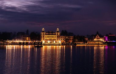 Velden, Avusturya - 20 Aralık 2024: Schlosshotel am Woerthersee, kış mevsimi boyunca, dingin suyu yansıtarak, şenlikli atmosferi artırarak gece parlar.