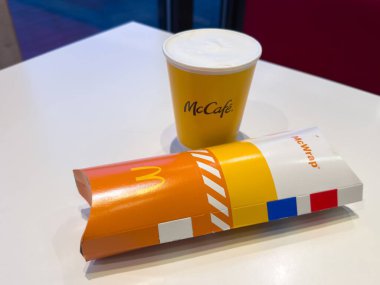 Villach, Avusturya - 25 Kasım 2025: McDonald 's McWrap ve kahve fincanı renkli markalaşma ve cazip fast food sunumunu vurguluyor