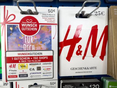 Villach, Avusturya - 02 Aralık 2025: H & M ve diğer perakendeciler için hediye kartları, canlı tasarımlar ve cazip tekliflerle dolu bir rafta sergileniyor