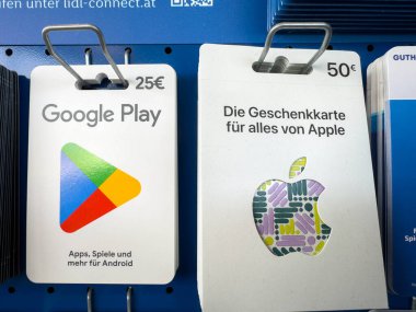 Villach, Avusturya - 02 Aralık 2025: Google Play ve Apple hediye kartları dijital hizmetleri ve renkli tasarımları ön plana çıkaran bir perakende satış ortamında sergilenmektedir