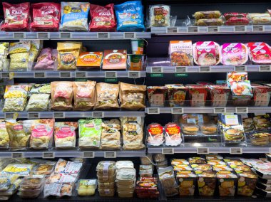 Villach, Avusturya - 10 Aralık 2025: Market raflarında paketli abur cuburlar ve hazır yemekler, müşterileri çeşitli mutfak seçeneklerini keşfetmeye davet etmek