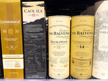 Villach, Avusturya - 10 Aralık 2025: Glenmorangie, Caol Ila ve The Balvenie 'nin karmaşık tasarım ve etiketleriyle raflarda sergilenen kaliteli viski şişeleri