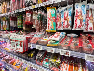 Villach, Avusturya - 10 Aralık 2025: Renkli ambalajlar ve cezbedici vitrinlerin yer aldığı çeşitli abur cubur ve şekerlerle dolu canlı bir market koridoru