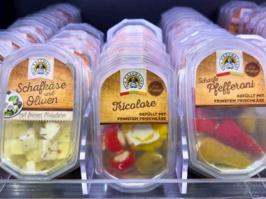 Villach, Avusturya - 10 Aralık 2025: Açık kaplarda çeşitli gurme peynirler ve zeytinler sergilenerek, taze malzemeler ve canlı renkler sunumu için ön plana çıkarıldı