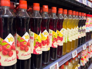 Villach, Avusturya - 10 Aralık 2025: Çeşitli aromalı içecek şişeleri süpermarket raflarında düzgün bir şekilde düzenleniyor, parlak renkler ve çekici etiketler sergileniyor