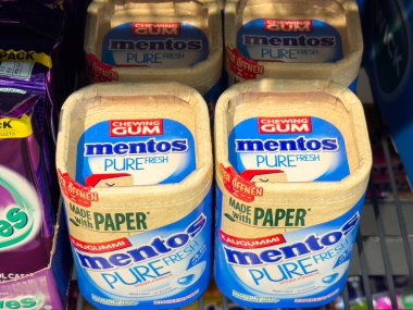 Villach, Avusturya - 10 Aralık 2025: Mentos Saf Çiklet paketleri bir mağaza rafında belirgin bir şekilde sergileniyor, çevre dostu kağıt paketlerini ve renkli tasarımı ön plana çıkarıyor