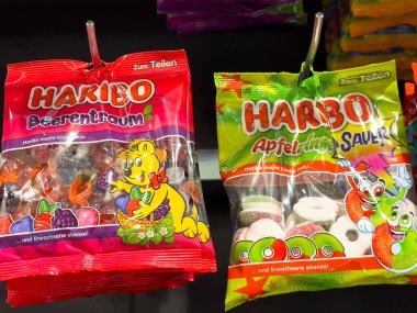 Villach, Avusturya - 10 Aralık 2025: Canlı renklerde HARIBO şekerleme paketleri, Ayı ve Elma aromalı, çekici tasarımlarla bir mağaza rafında sergilendi