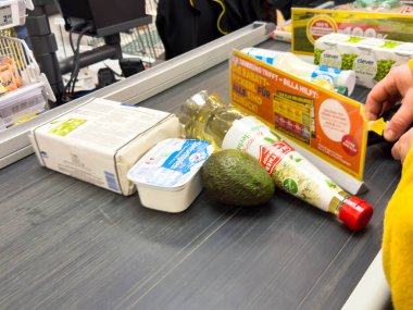 Villach, Avusturya - 10 Aralık 2025: Avokado, petrol ve süt ürünleri gibi market ürünleri, marketteki konveyör üzerinde, sağlıklı alışveriş alışkanlıklarını ön plana çıkararak,