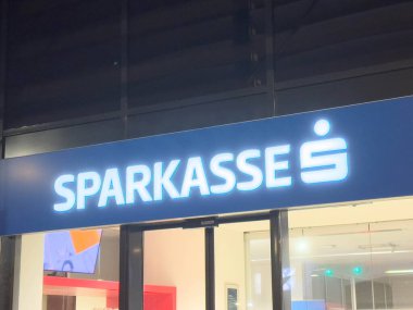 Villach, Avusturya - 10 Aralık 2025: Geceleri parlayan Sparkasse banka tabelası, bankacılık çözümleri arayan müşteriler için çağdaş tasarım ve karşılama ortamını vurguluyor