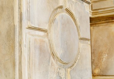 Yuvarlak kabartmalı antik taş duvar ve sepia tonlarında yıpranmış doku.