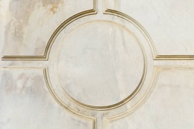 Yıpranmış taş yüzeyinde karmaşık detaylarla geometrik dairesel desen.