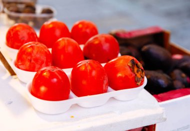 Pazar yerinde sergilenen taze kırmızı domatesler ve avokadolar.