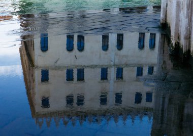 Sudaki yansıtıcı mimari: mavi pencereli tarihi bina.