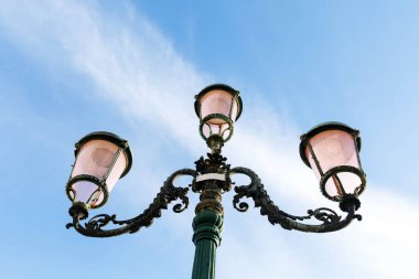 Açık mavi gökyüzüne karşı süslü tasarımı olan zarif klasik sokak lambası..