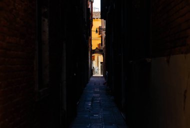 Venedik, İtalya - 05 Aralık 2025: Venedik 'te dar bir sokak, güneş ışığıyla yıkanmış, tuğla duvarlar ve kaldırım taşları, huzurlu bir kent manzarasını çağrıştırıyor