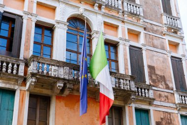 Venedik, İtalya - 05 Aralık 2025: Venedik, İtalya 'daki tarihi bir binada Avrupa bayrakları sergileniyor, şehrin mimari güzelliği ve canlı renkleri vurgulanıyor