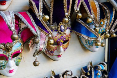 Venedik, İtalya - 05 Aralık 2025: Canlı Venedik maskeleri, karmaşık tasarımlarını ve kültürel önemini vurgulayan bir duvara güzelce yerleştirilmiştir