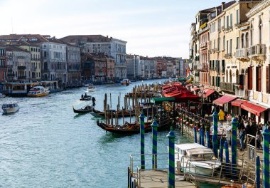 Venedik, İtalya - 05 Aralık 2025: Gondol Venedik 'teki Büyük Kanal boyunca süzülüyor, renkli binalar ve renkli kafelerle çevrili güzel bir atmosfer yaratıyor.