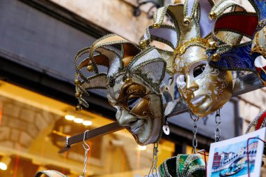 Venedik, İtalya - 05 Aralık 2025: Venedik 'ten gelen renkli maskeler, karmaşık tasarımları ve şenlikli ruhlarını ön plana çıkaran bir sokakta güzel bir şekilde sergilenmektedir.