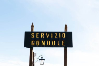 Venedik, İtalya - 05 Aralık 2025: Venedik, İtalya 'da Gondol servis tabelası, açık mavi gökyüzü ile geniş bir kopya alanı sağlayan geleneksel işçiliği vurguluyor