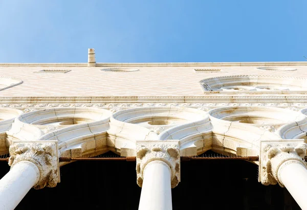 Venedik, İtalya - 05 Aralık 2025: Tarihi bina arka planda parlak mavi bir gökyüzü ile aşağıdan bakıldığında karmaşık sütunlar ve kemerler barındırıyor